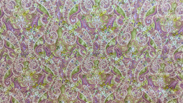 A linen fabric with an intricate paisley pattern in warm, earthy tones of muted greens, purples, and pinks, accented by floral motifs.