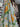 Floral fabric with yellow and white flowers on a polka dot background, hanging in a store setting