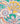 A close-up of a colorful paisley and floral patterned fabric or wallpaper featuring yellow, green, pink, orange, and purple motifs.