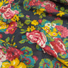 Colorful floral fabric with pink, yellow, and red flowers on a dark background