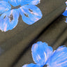 Close-up of printed pure cotton fabric, with floral patterns in blue and lilac on a black base. 