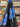 Printed pure cotton fabric, with floral patterns in blue and lilac on a black base, shown draped within a shop setting.