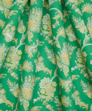 A close-up of draped green fabric with an all-over floral toile pattern in pale yellow, cream, and light blue.
