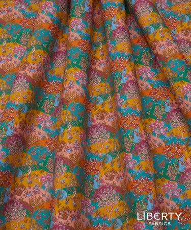 A close-up of draped Liberty Fabrics featuring a vibrant, multicolor floral and paisley pattern with yellow, teal, pink, and orange tones.