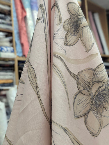 Close-up of fabric with sepia-toned daffodil pattern on light pink base draped in a shop setting