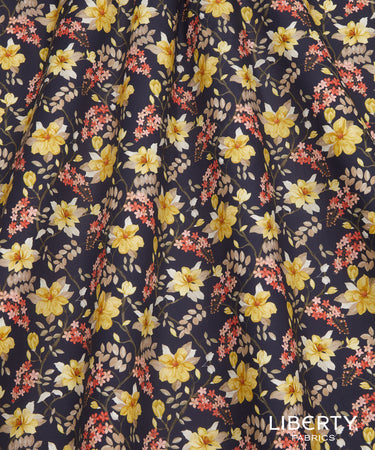 A close-up of Liberty Fabrics floral fabric with a navy blue background, featuring yellow, white, and red flowers with green leaves.
