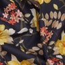 A close-up of a draped fabric with a dark navy background and a floral pattern featuring yellow, pink, and red blossoms with beige leaves. The brand name 'LIBERTY FABRICS' is visible in the bottom right corner.