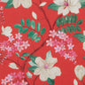 A close-up of a Liberty Fabrics floral pattern featuring cream magnolia flowers, pink blossoms, and green leaves on a vibrant red background.
