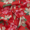 A close-up of draped Liberty Fabrics featuring a red floral pattern with pink blossoms, cream-colored magnolia flowers, and green leaves.