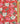 A close-up of a Liberty Fabrics floral fabric with a red background, featuring white magnolia flowers, pink blossoms, and green leaves, with a gold ruler on the right side for scale.