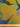 Textured fabric with abstract pattern in yellow, green, and blue, shown with a ruler at the bottom for scale.