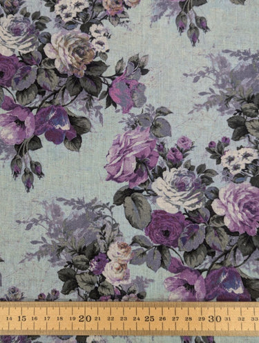 Floral fabric pattern with purple and grey flowers on a light blue background, measured with a ruler at the bottom.