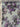 Floral patterned fabric with purple and grey flowers on a light blue background, featuring the selvedge with the brand 'Carnet' and 'Made in Italy'.