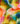 A close-up of colorful tie-dye or watercolor-patterned fabric with blended shades of yellow, pink, blue, green, orange, and white. The Liberty Fabrics logo appears in the bottom right corner.