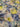 A linen fabric featuring a floral pattern with shades of blue, yellow, and grey, giving an impressionist garden look.