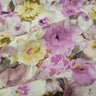 A close up of a linen fabric featuring a floral print with soft colours like pink and yellow