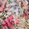 A close-up of a Liberty Fabrics floral fabric with a dense watercolor-style print featuring pink, white, yellow, and green flowers on a dark background.