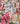 A close-up of a Liberty Fabrics floral fabric with a dense watercolor-style print featuring pink, white, yellow, and green flowers on a dark background.