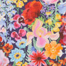A close-up of a colorful floral fabric pattern with large and small watercolor-style flowers in pink, red, yellow, blue, orange, and purple on a dark navy background. 