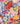A close-up of a colorful floral fabric pattern with large and small watercolor-style flowers in pink, red, yellow, blue, orange, and purple on a dark navy background. 