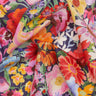 A close-up of draped fabric featuring a vibrant watercolor floral print on a dark navy background. The print includes large flowers in pink, red, orange, yellow, and white, interspersed with green leaves and purple accents.