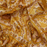 A close-up of draped Liberty Fabrics featuring a golden yellow and beige ikat pattern with brown accents.