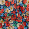 A close-up of a Liberty Fabrics floral fabric print featuring red poppies, cream daisies, and blue flowers on a dark navy background.