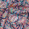 A close-up of a multicolor paisley fabric with intricate floral and ornamental patterns on a dark navy background. The fabric is draped to show its texture and pattern density.