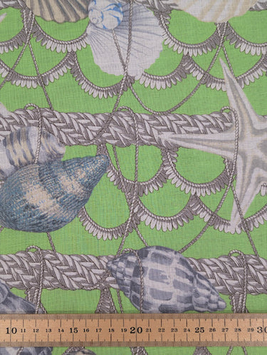 Fabric with nautical pattern featuring shells and ropes on a green background, with a ruler at the bottom for scale.