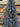 A printed pure cotton batiste, with a geometric motif in cobalt blue, ivory, and black, with interlocking circles and angular lines, shown draped within a shop setting.