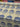 Printed pure cotton fabric with large blue floral motifs on an ivory ground, shown unrolled on a table.