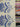 Printed pure cotton fabric with large blue floral motifs on an ivory background, held up within a shop setting to show the transparency of the fabric.