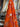 Close-up of a printed pure wool fabric with intertwined ropes, tassels, and chains on a vivid orange ground, draped within a store setting