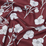 A close-up of draped Liberty Fabrics featuring a deep burgundy red satin-like fabric with a white floral print.