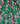 A close-up of Liberty Fabrics floral patterned fabric, featuring a vibrant green background with a bright pink floral print. The fabric is draped in soft folds, showcasing its texture and weight.