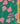 A close-up of Liberty Fabrics featuring a vibrant green background with a bright pink floral pattern, with a wooden ruler on the right side for scale.