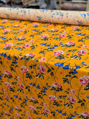 Bolt of floral fabric with pink and blue flowers on an orange background