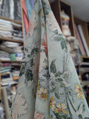 Floral fabric swatch held up against a blurred fabric store background