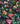 A close-up of Liberty Fabrics floral print fabric with a dark navy background and colorful flowers including pink, orange, yellow, and blue blossoms with green leaves.