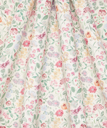 A close-up of draped fabric with a delicate, multicolor floral print on a cream background. The pattern features pink, red, yellow, and light blue flowers with green leaves and stems.