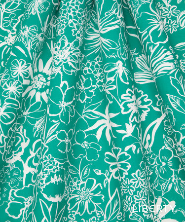 A close-up of a teal green fabric with a white floral and botanical line pattern, showing soft folds and a sheer, lightweight texture.