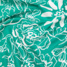 A close-up of a teal green fabric with a white floral line-art pattern, showing soft folds and a visible Liberty Fabrics logo in the bottom right corner.