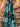 Pure wool fabric draped with painterly florals in green, black and blue draped within a shop setting