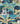 A close-up of Liberty Fabrics featuring a tropical botanical pattern with palm trees, banana leaves, and other foliage in shades of teal, green, yellow, and light blue on a dark navy background.