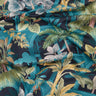 A close-up of draped Liberty Fabrics featuring a tropical botanical print with palm trees, monstera leaves, and blue flowers on a dark navy background with teal arches.