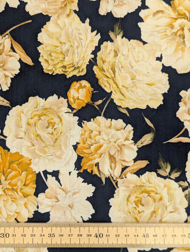 Close-up of a printed pure wool fabric featuring yellow florals on a navy background, with a ruler at the bottom for scale.
