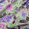 A linen fabric with a bold floral print featuring primarily blue, pink and grey colours on a green background.