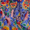 A close-up of a colorful printed fabric with a bold floral and paisley pattern in blue, pink, red, yellow, green, and white, with a visible Liberty Fabrics logo in the bottom right corner.